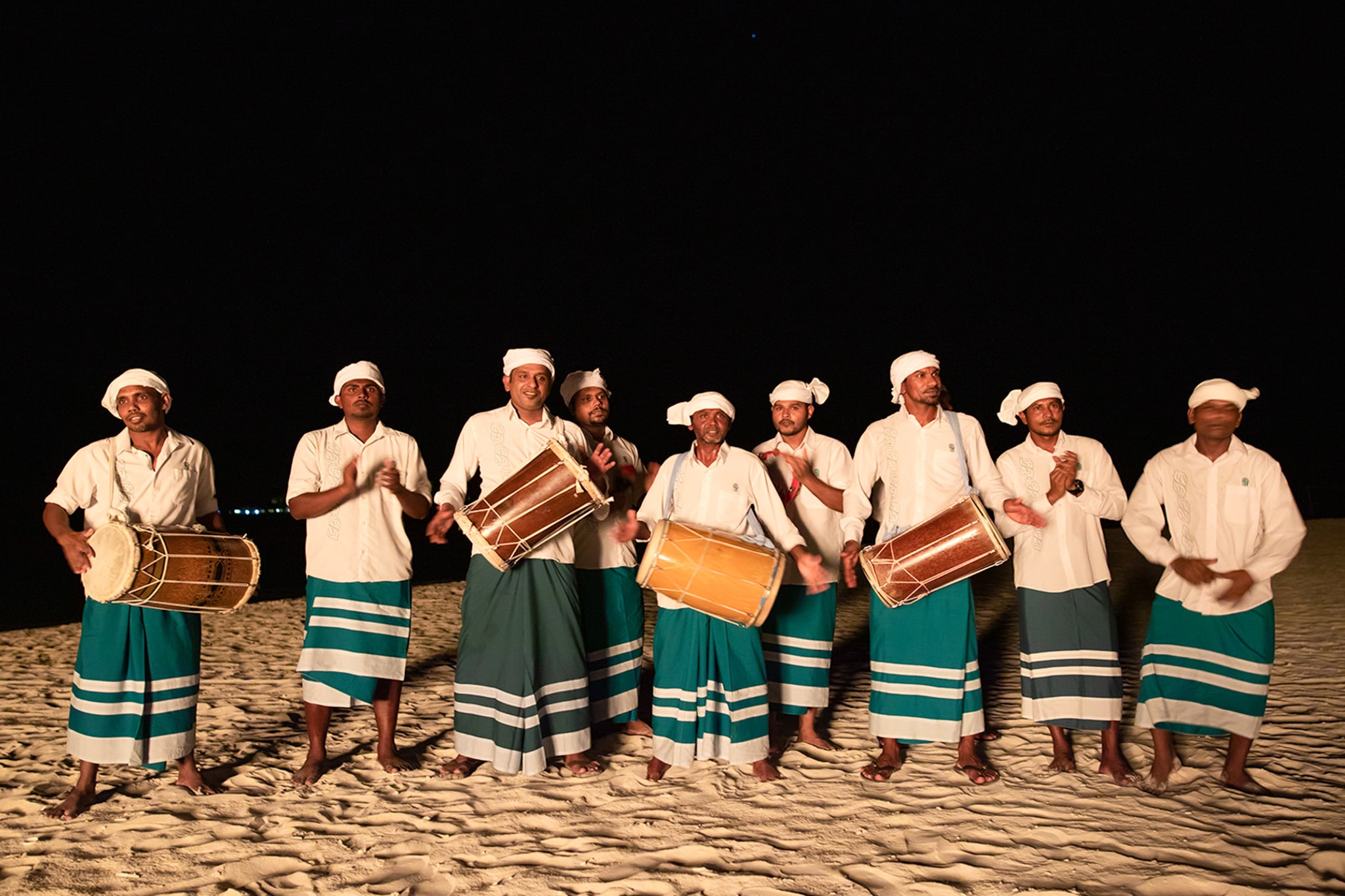 a group of people standing on top of a sandy beach in Velavaru, Maldives